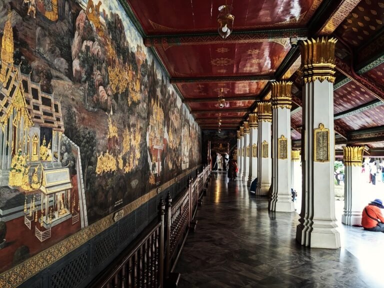 Ramakien mural along a corridor in Thailand, featuring ornate gold details and figures.