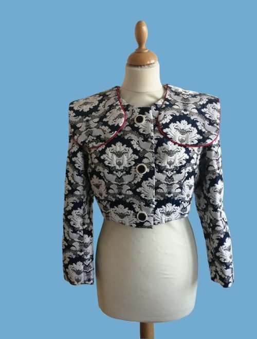 Navy blue and white patterned cropped jacket with red trim on mannequin